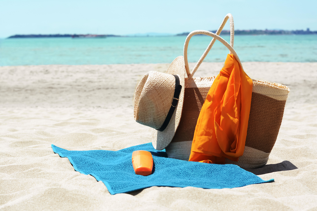 Blue towel, bag and beach accessories on sandy seashore, space for text